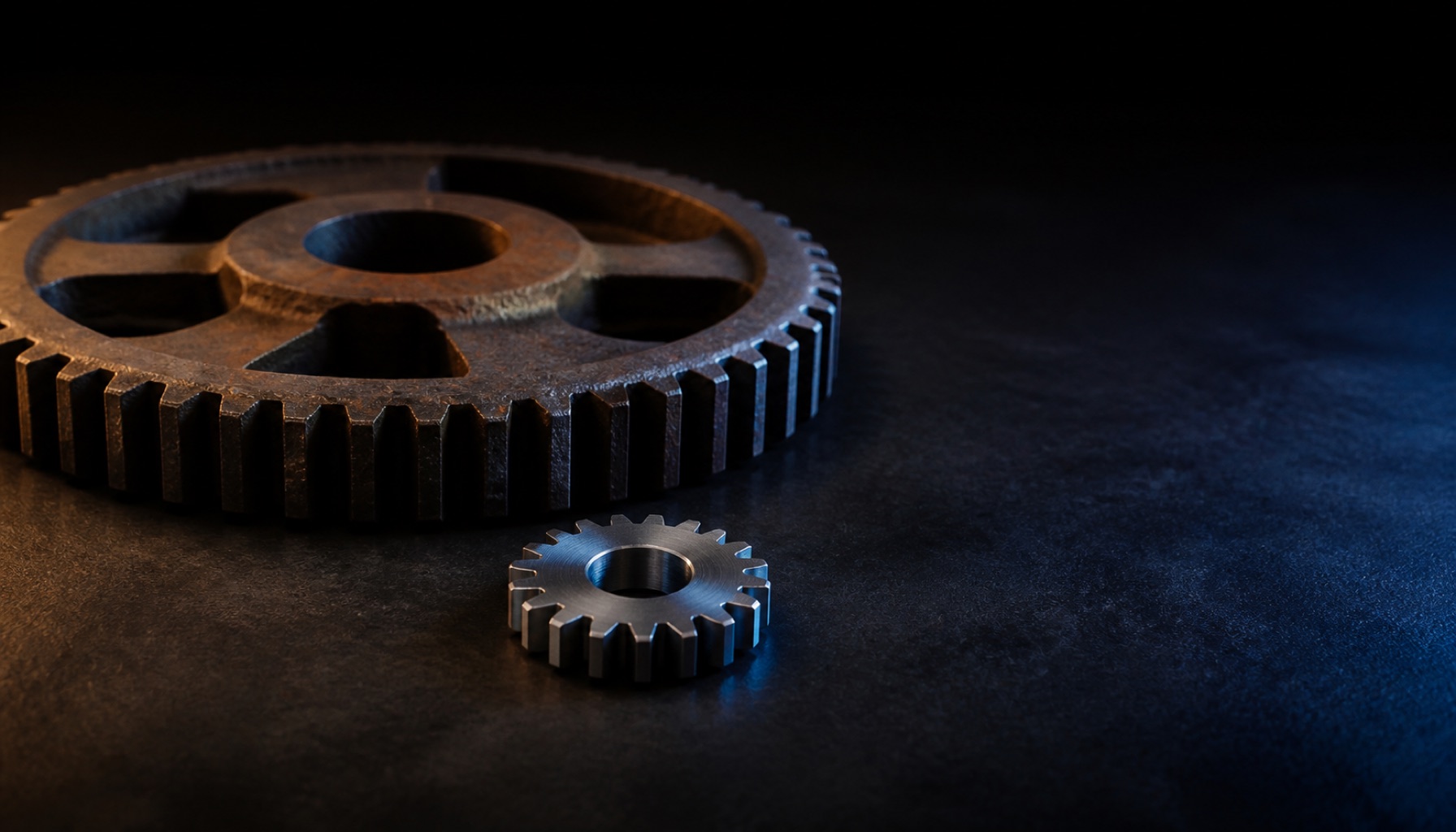 A heavy cast-iron industrial gear beside a small modern machined gear of the same shape